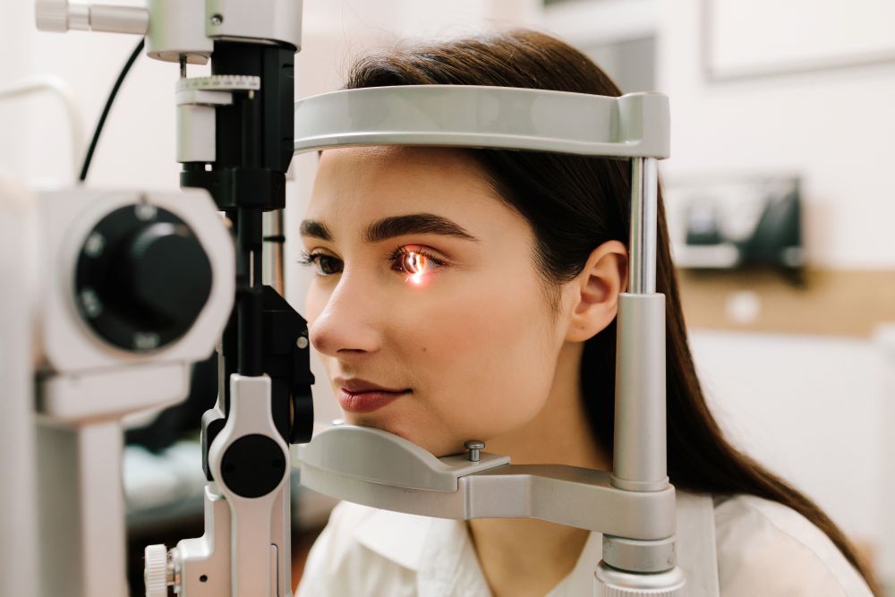 A young woman positioned in front of a slit lamp during a comprehensive eye examination